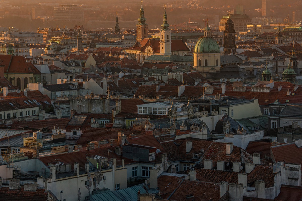 European rooftops and church towers under a low evening sun